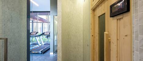 A hallway with a treadmill, wooden walls, and a tiled floor.
