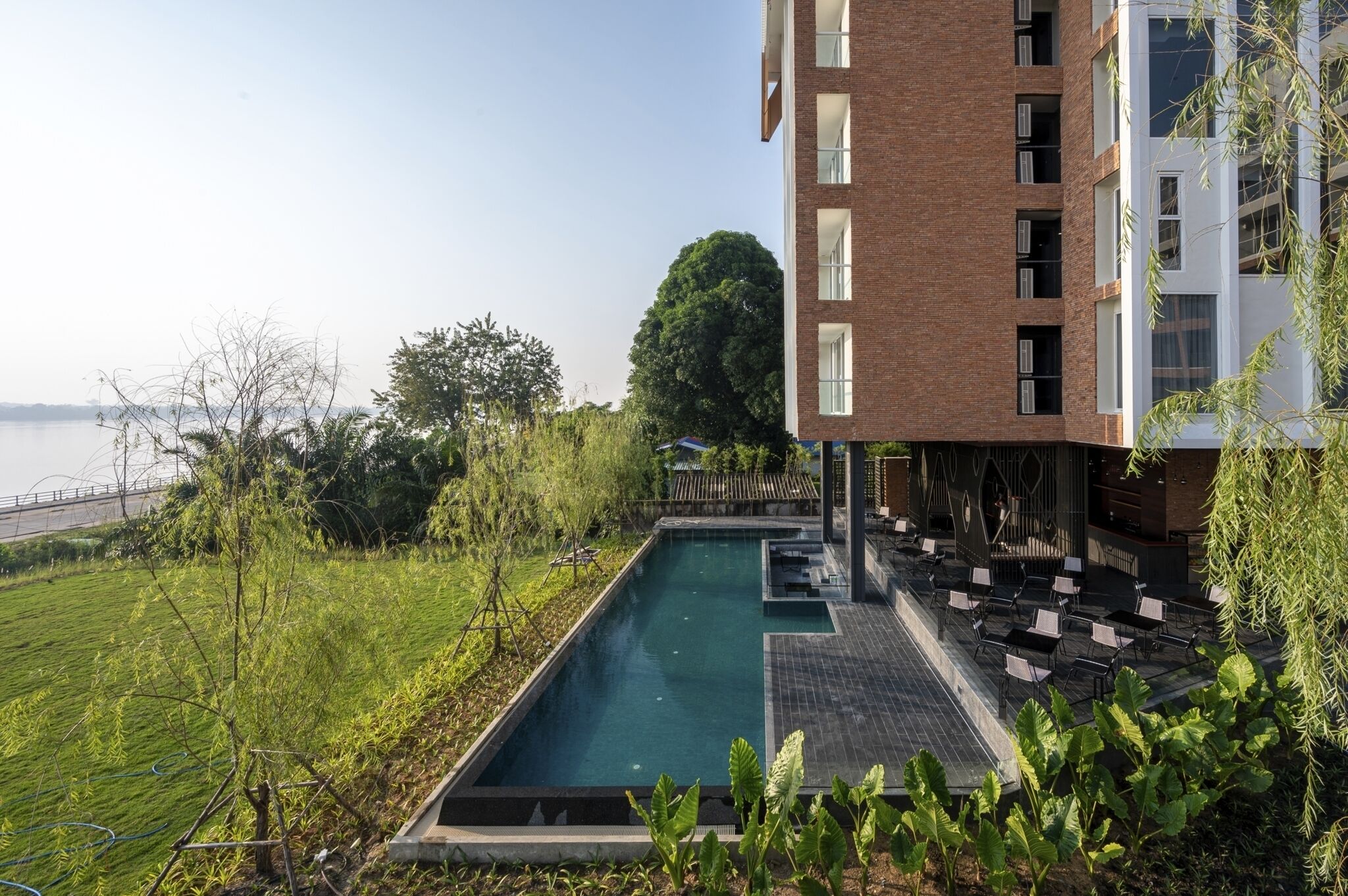 Un edificio moderno con piscina, mobiliario exterior y vista al agua.
