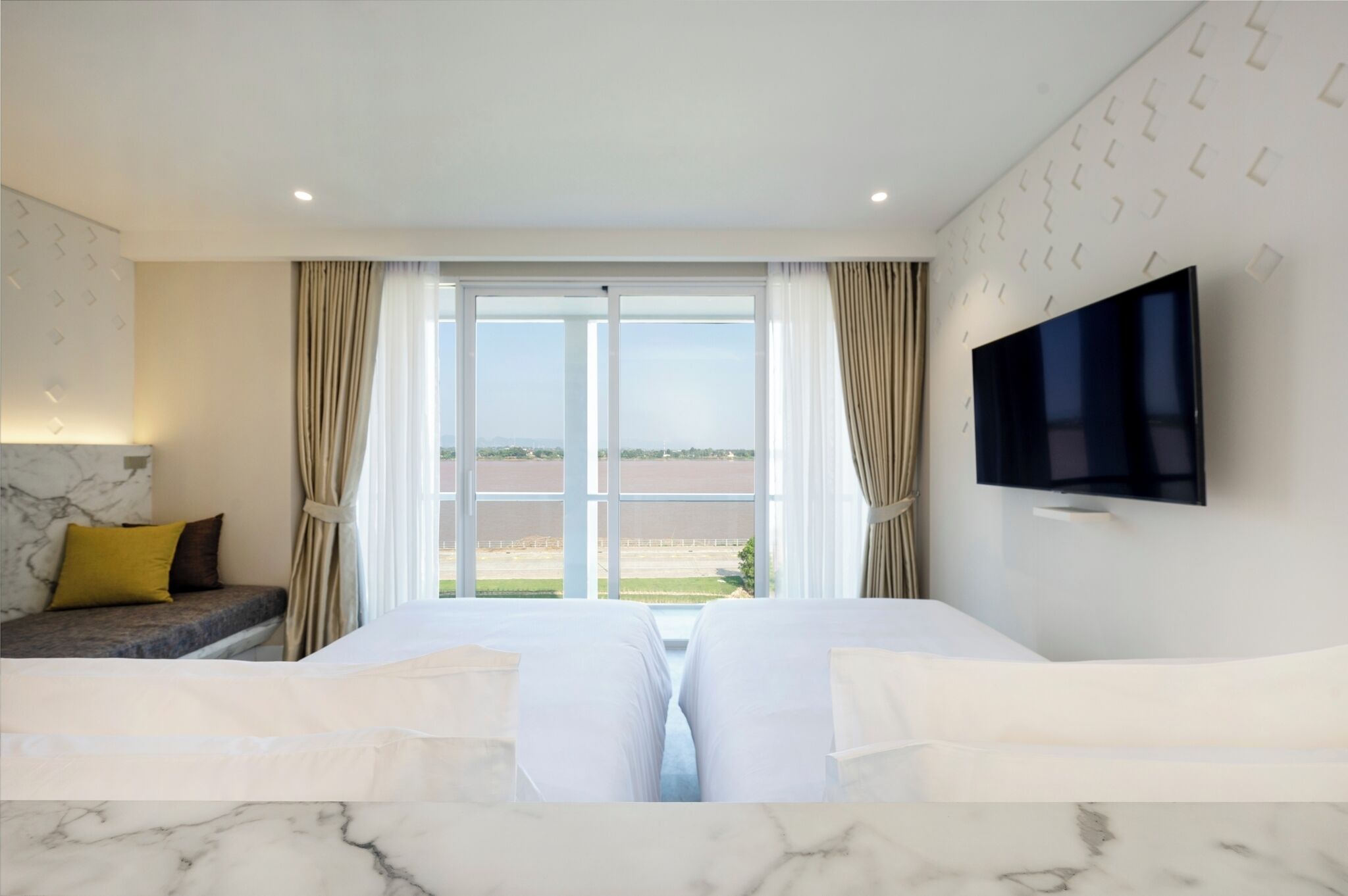 Habitación de hotel con una cama grande, un televisor montado en la pared y vistas al paisaje a través de la ventana.