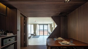A modern hotel room with a dining area, a kitchen, and a view of the outdoors. - VELA Dhi Nakhon Phanom (Nakhon Phanom)
