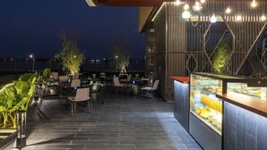 An outdoor patio with seating and a glass display case of food items. - VELA Dhi Nakhon Phanom (Nakhon Phanom)