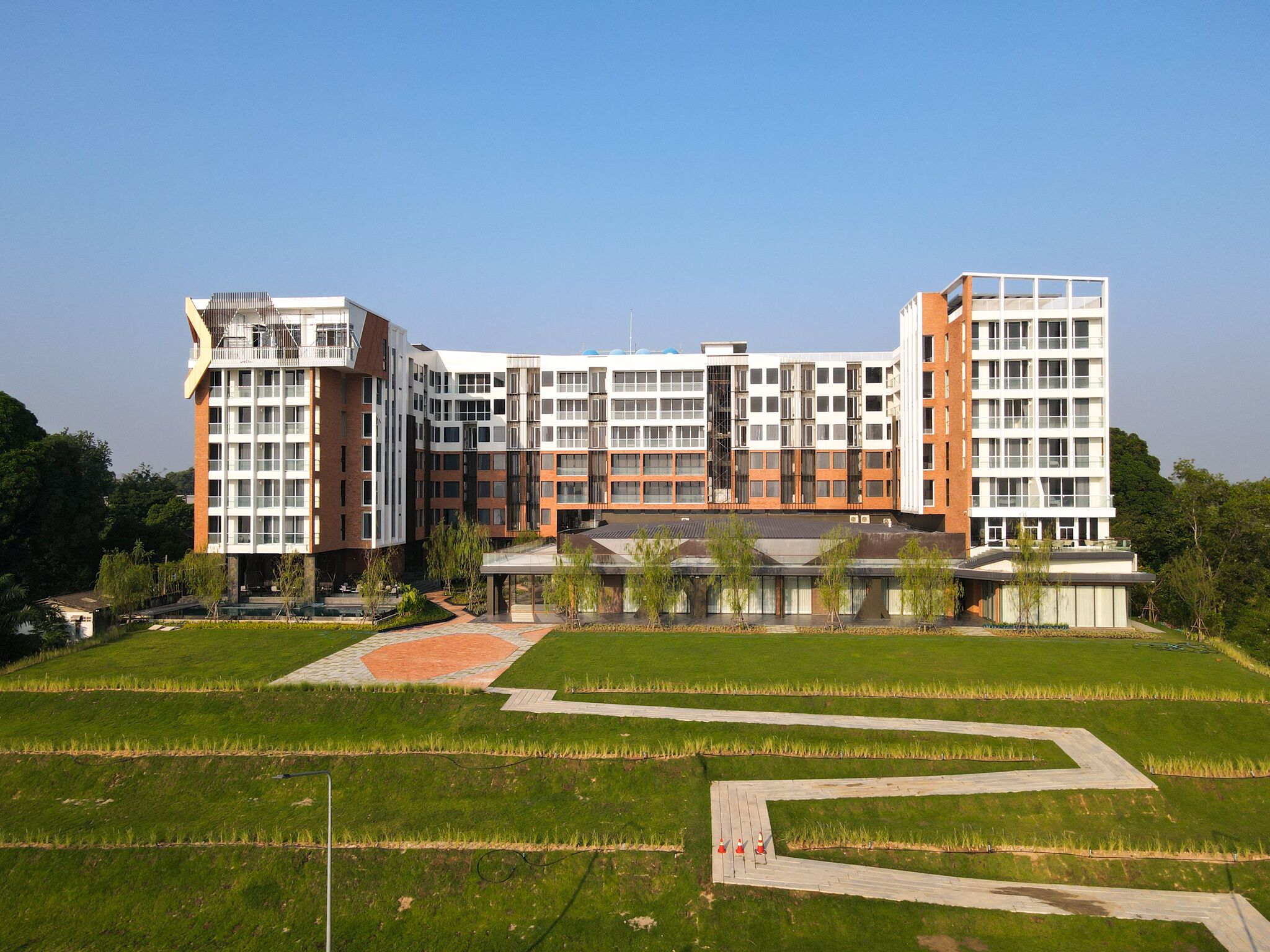 Un edificio a più piani con un design architettonico moderno, caratterizzato da un rivestimento in mattoni e vetro.