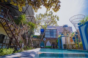 Une piscine avec un toboggan, un panier de basketball et une structure d’escalade.