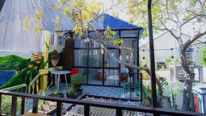 A small house with a blue roof, large windows, and a balcony with potted plants. - 86 Homestay Phan Thiet (Phu Thuy)