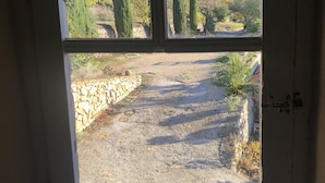 A view through a window with a stone wall and a gravel path leading outside. - Lovely, sunny, very quiet apartment facing south in Sanary sur mer  (Sanary-sur-Mer)