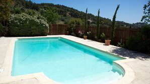 A rectangular swimming pool with a tiled deck, surrounded by a wooden fence and various potted plants. - Lovely, sunny, very quiet apartment facing south in Sanary sur mer  (Sanary-sur-Mer)