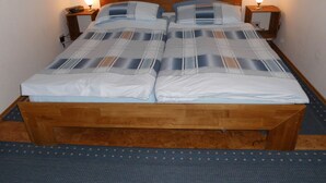 Un lit double avec un cadre en bois, deux tables de chevet avec des lampes et un tapis bleu à motifs.