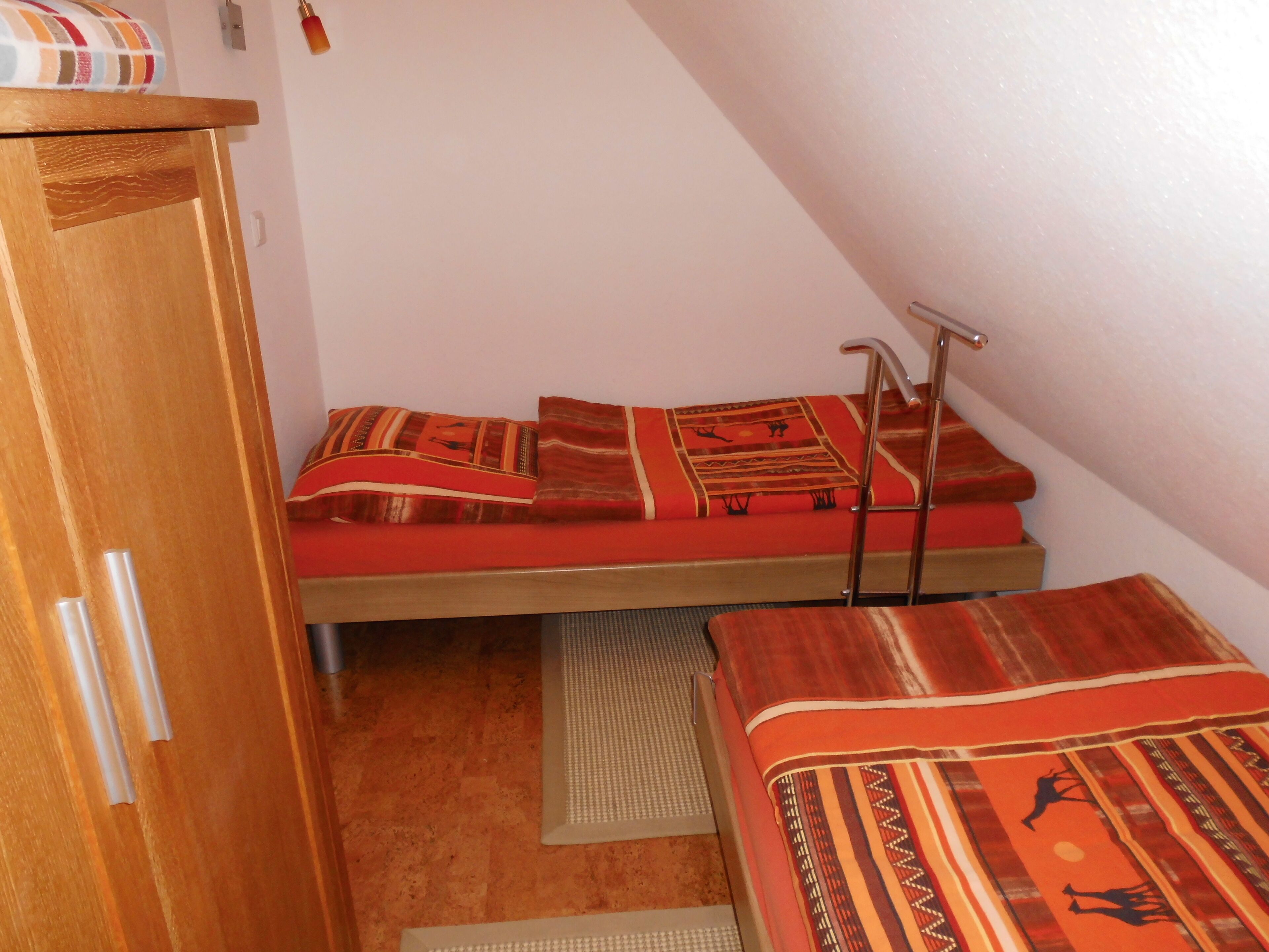 Habitació petita i senzilla amb un llit superposat, un armari de fusta i una escala.