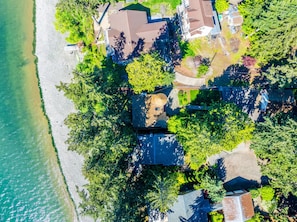 An aerial view of a coastal residential area with houses, a beach, and dense greenery. - Fairyland Cottage: Waterfront+Hot Tub+Beach+Clam (Poulsbo)