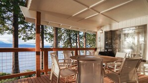 A covered outdoor dining area with a view of the water and trees. - Fairyland Cottage: Waterfront+Hot Tub+Beach+Clam (Poulsbo)