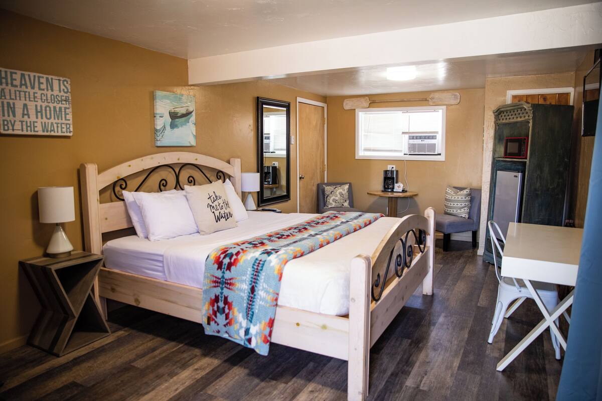 A well-lit bedroom with a bed, bedside tables, a chair, and a desk.