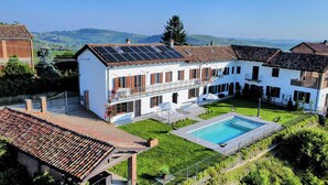 Ein zweistöckiges Gebäude mit Schwimmbad, Solaranlage und gepflegtem Rasen.