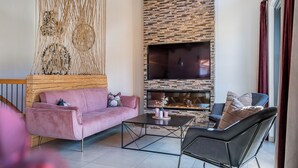 Una sala de estar moderna con chimenea, un sofá rosa, una silla negra y un adorno de pared de madera.
