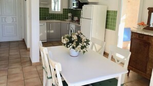 Eine kompakte Küche mit Essbereich, mit einem weißen Tisch, Stühlen und einem Topfpflanzen.