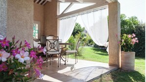 Eine Terrasse im Freien mit Tisch, Stühlen, einer Pergola und Blick auf einen Garten.
