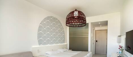 Habitación de hotel moderna con una cama grande, un sofá, una mesita redonda y un televisor.