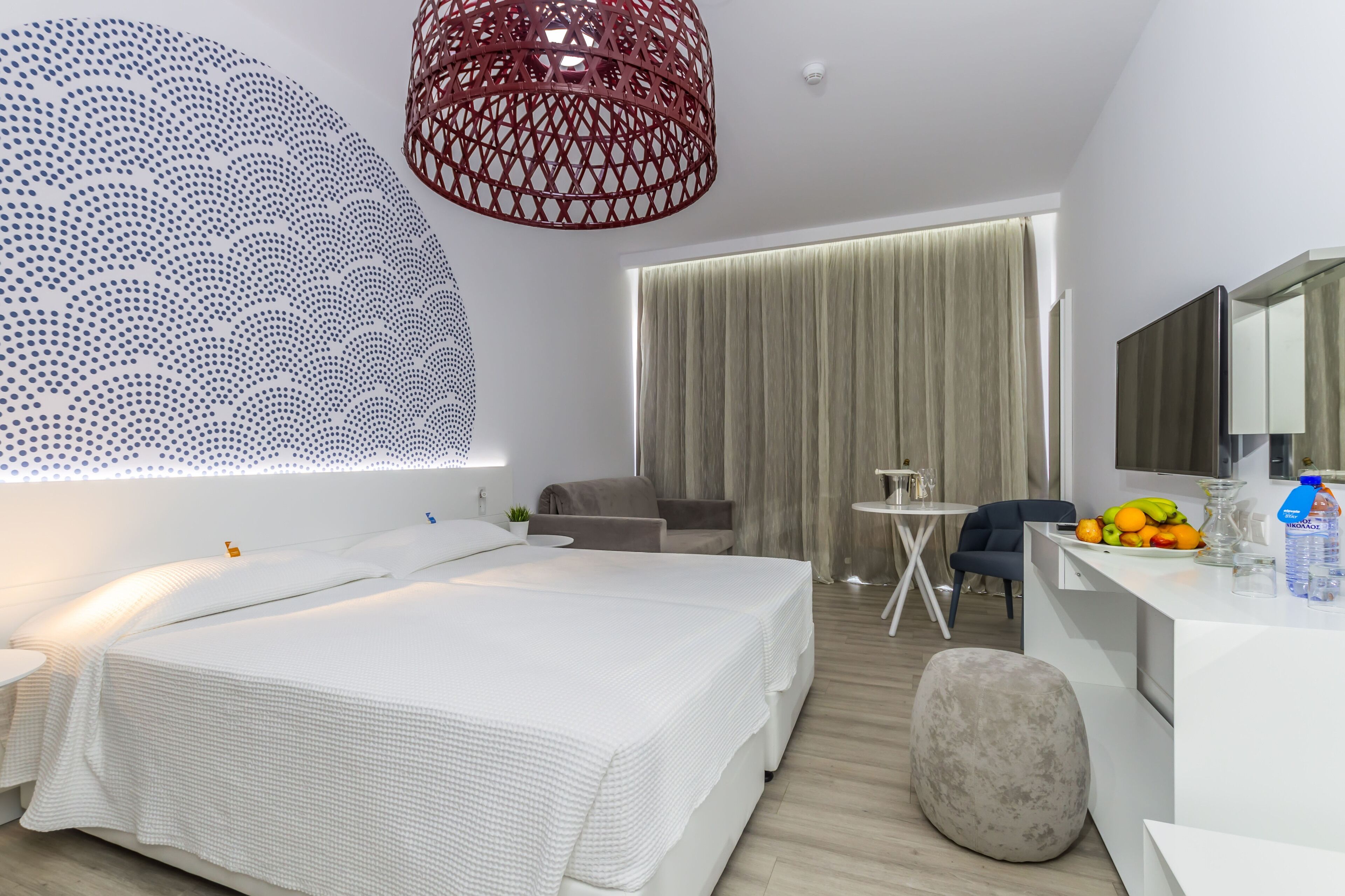 Moderni hotellihuone, jossa on suuri sänky, työpöytä, tuoli ja ruokapöytä.