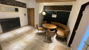 Un intérieur moderne avec un coin repas comprenant une table ronde et quatre chaises, un mur d’accent en pierre et un radiateur situé à gauche.