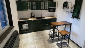 Une cuisine moderne avec des meubles de couleur vert foncé, une table en bois et un sol carrelé.