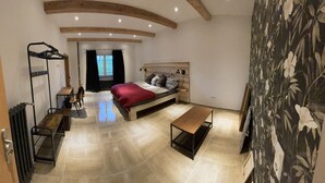 Une chambre à coucher avec un lit, un banc, un radiateur, un miroir et une fenêtre avec des rideaux.