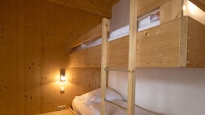 Habitación con literas, paredes de madera y una lámpara fijada a la pared.