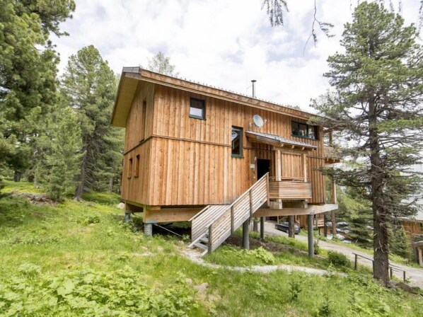 A wooden cabin with a balcony and a staircase, surrounded by trees. - #37 mit IR-Sauna und Sprudelbad Innen by Interhome (Turracher Höhe)
