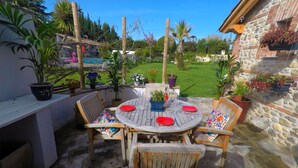 An outdoor patio with a round table, wooden chairs, and potted plants. - Mas Des Fleurs - Heated pool - Child friendly gardens - Beach 10mins   (Perpignan)