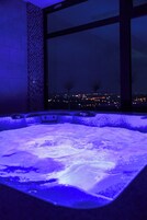 Un jacuzzi con vistas a un paisaje urbano nocturno.