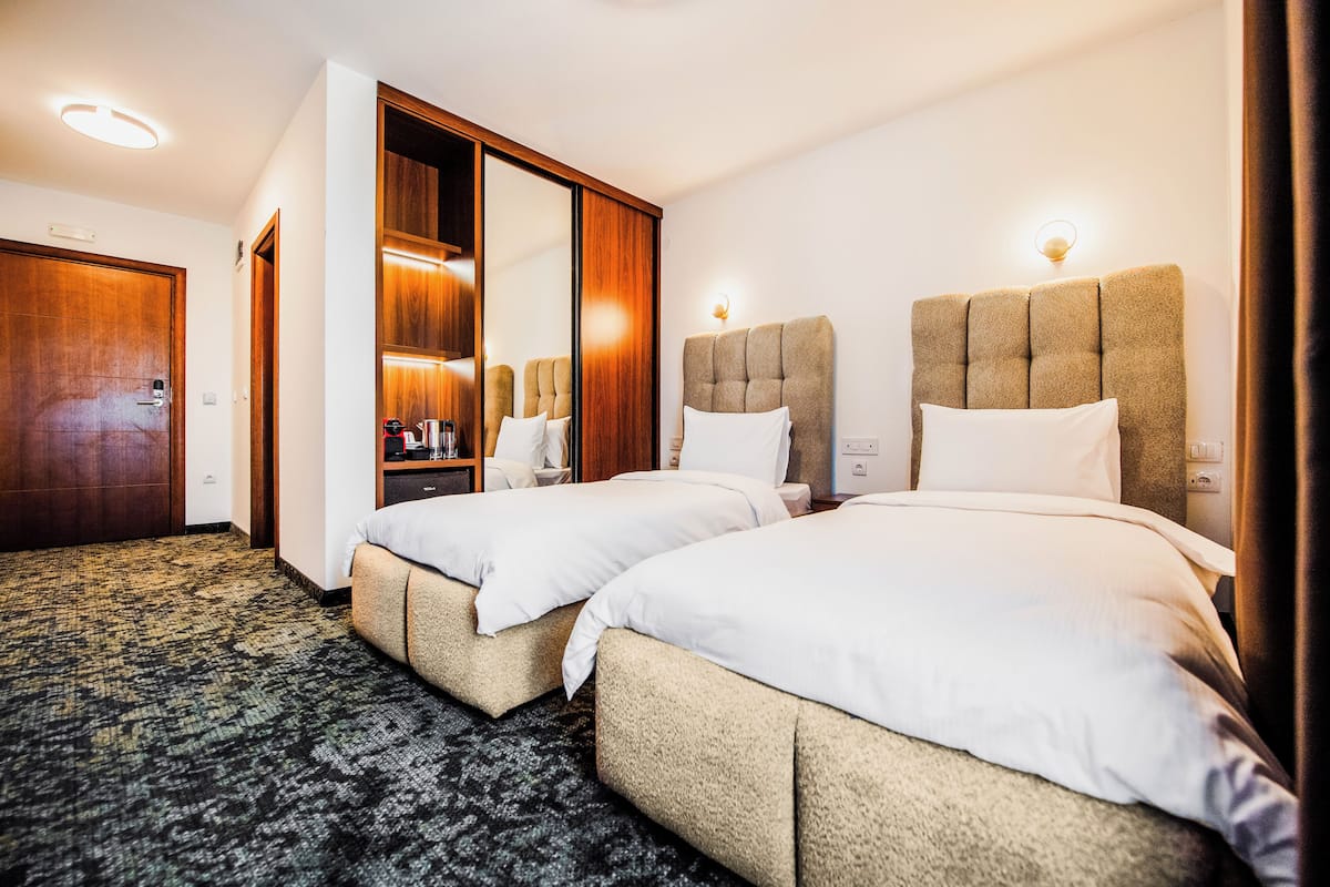 A hotel room with two beds, a wardrobe, a mirror, and a carpeted floor.