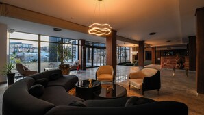 A spacious lobby with modern furniture, large windows, and a unique ceiling light fixture. - Alexander Resort (Belgrade)