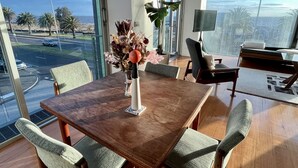 Un comedor moderno con una mesa y sillas de madera, un florero con flores y una planta grande.