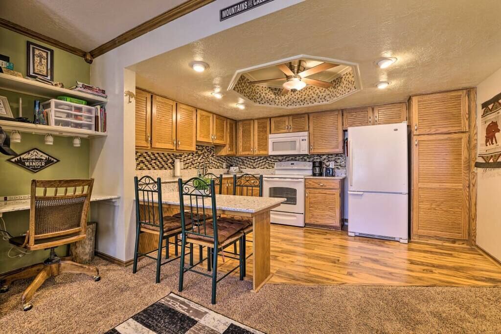 A kitchen with wooden cabinets, a white refrigerator, a microwave, and a dining area with a table and chairs.