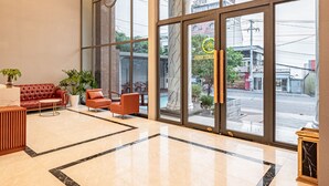 A spacious lobby with a large seating area, a reception desk, and large windows offering a view of the street. - TAHITI CENTRAL HOTEL (Phu Quoc)
