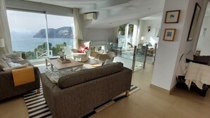 A modern living room with a sofa, a coffee table, and a view of the sea.