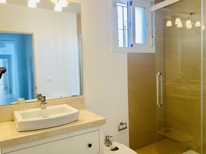 Ein modernes Badezimmer mit einem großen Spiegel, einem Waschbecken und einer Duschkabine.