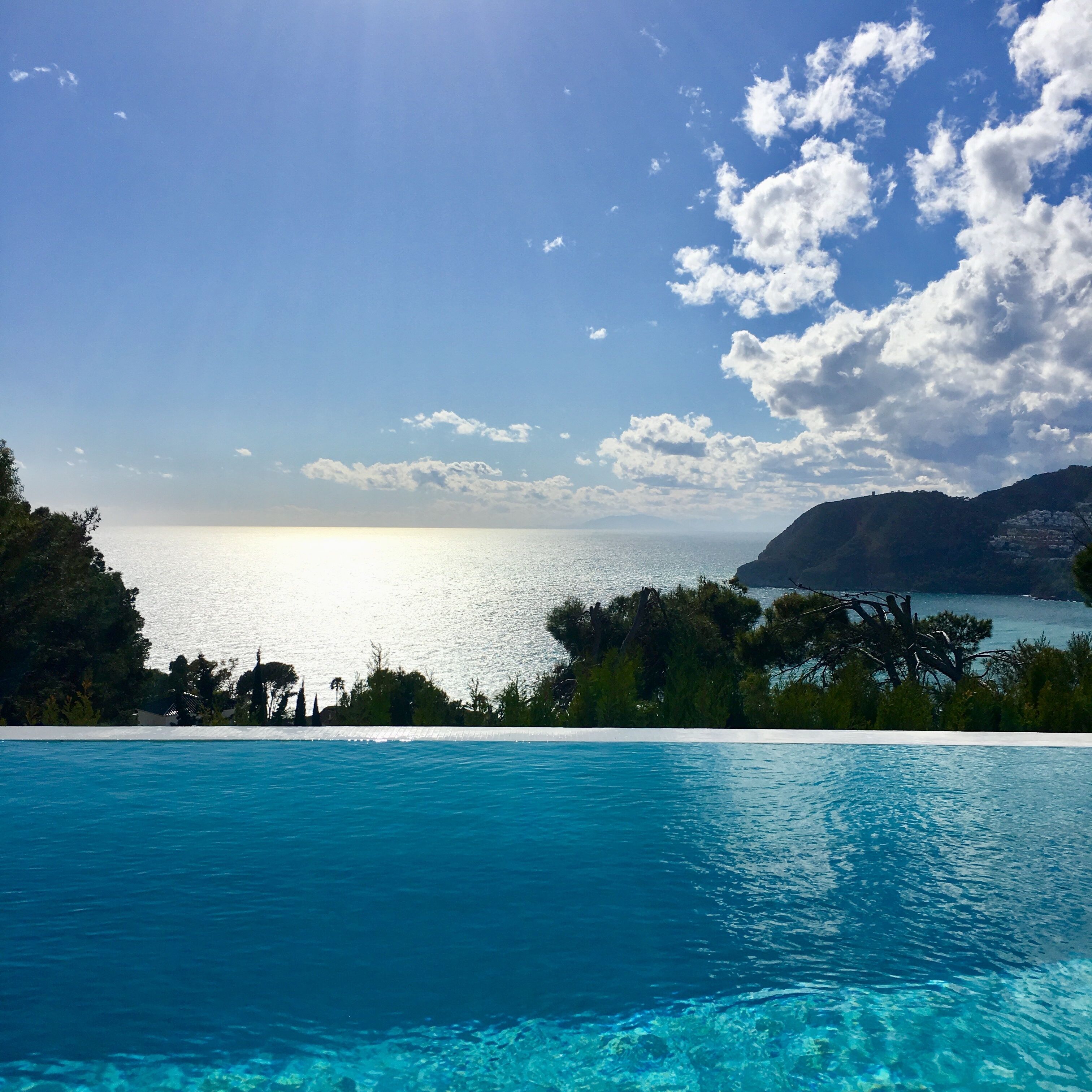 A clear blue sky, a swimming pool, and a view of the sea.