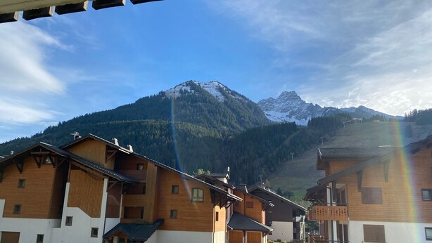 Un village de montagne avec des bâtiments en bois, une voiture garée devant, et un ciel dégagé.