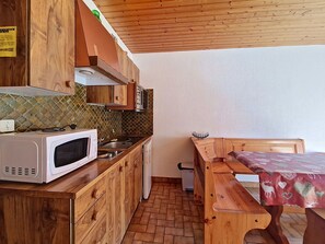 Une cuisine compacte avec des meubles en bois, un four à micro-ondes, un évier et un petit réfrigérateur.