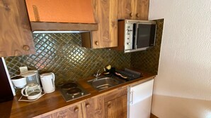 Une cuisine avec des meubles de rangement en bois, un four à micro-ondes, un évier et un petit réfrigérateur.