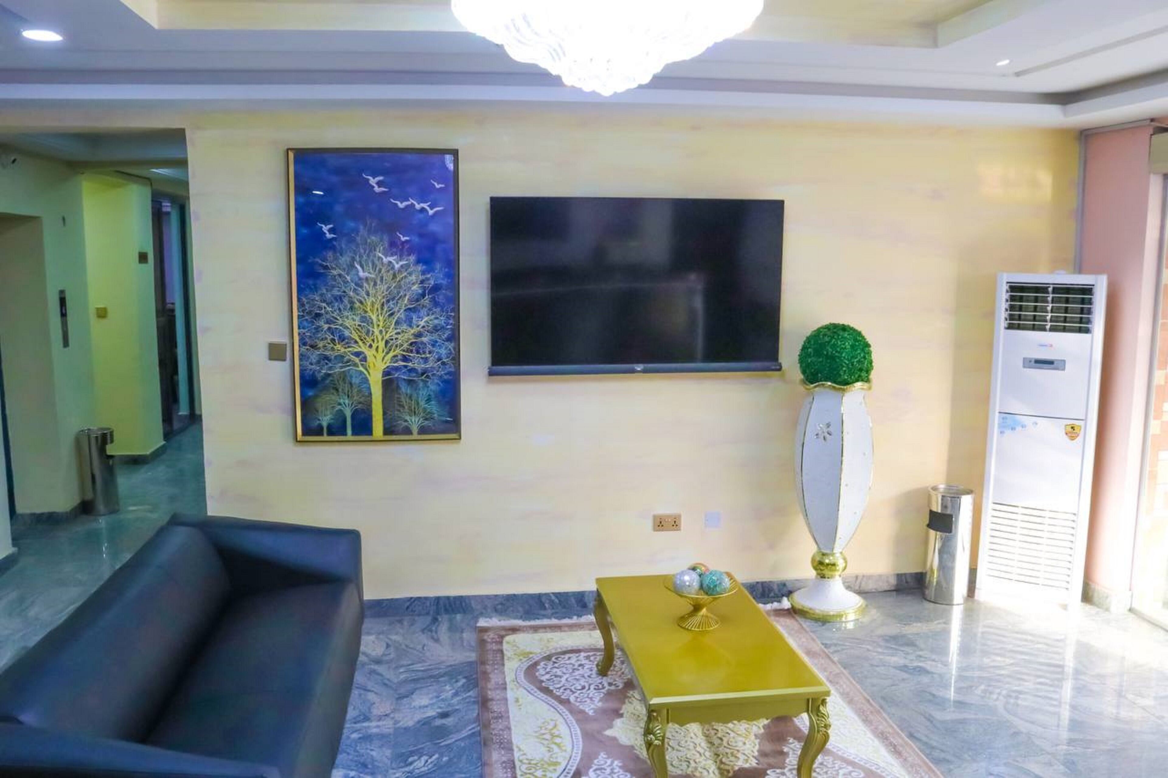 A living room with a sofa, a coffee table, a TV, and a painting on the wall.