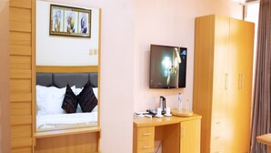 A hotel room with a bed, a desk, a TV, and a wardrobe. - Madaki's Executive Suites (Abuja)