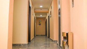 A hallway with marble flooring, beige walls, and doors on both sides. - Madaki's Executive Suites (Abuja)
