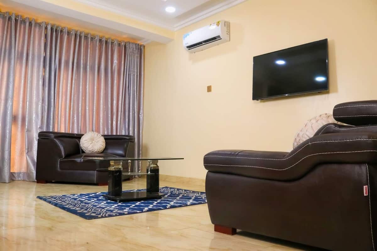 Una sala de estar con sofá, mesa de centro, televisor y aire acondicionado.