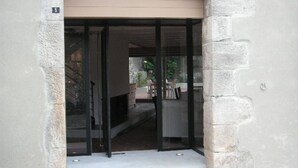 A building entrance with a glass door and a brick archway. - Luxury House - Exceptional (Roquefort-des-Corbières)