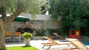 An outdoor patio with a stone wall, a pizza oven, lounge chairs, and a small pool. - Luxury House - Exceptional (Roquefort-des-Corbières)