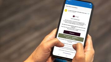 Eine Person hält ein Smartphone mit einer Hotelsuchseite.