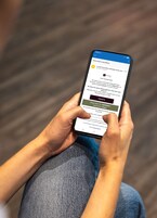Una persona sosteniendo un teléfono inteligente con una interfaz de reserva de hotel.