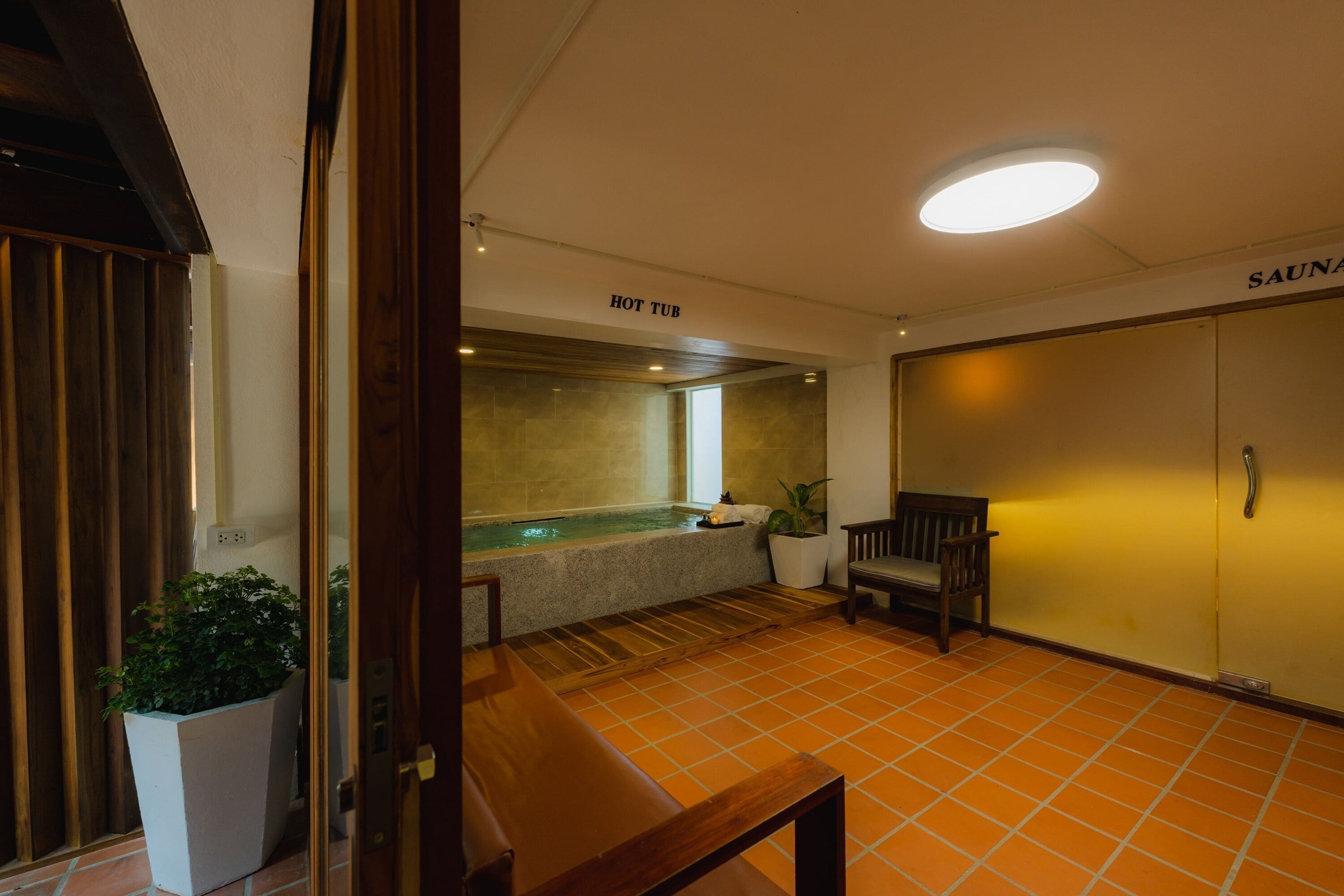A spa area with a hot tub, a wooden bench, and a sauna room.