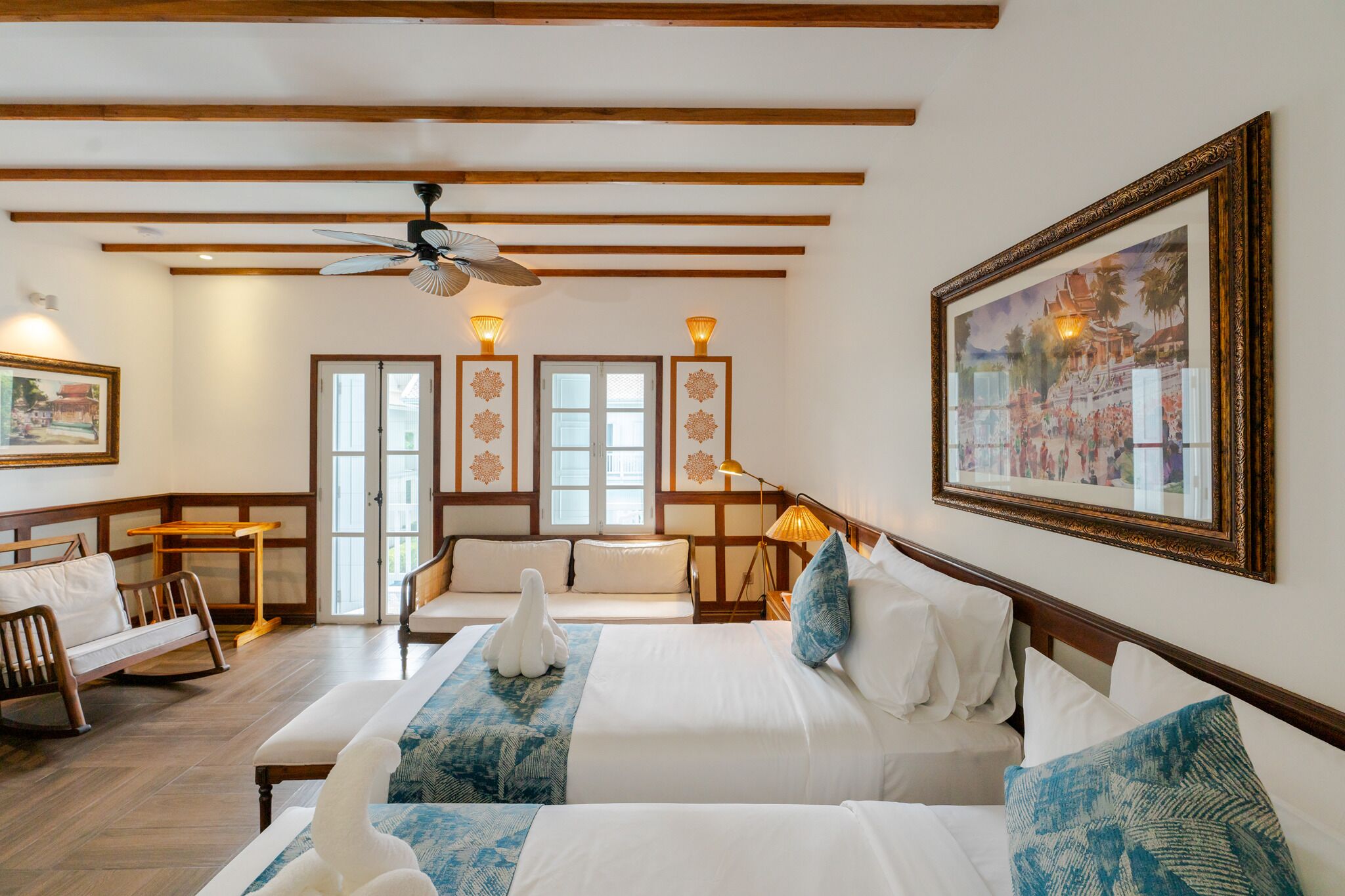 Een hotelkamer met een groot bed, een sofa, een kleine tafel en een plafondventilator.