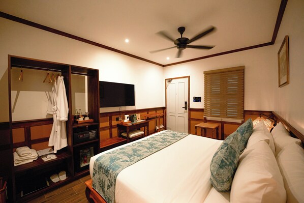 A hotel room with a bed, a television, a desk, a wardrobe, and a ceiling fan. - Mybanlao Hotel (Luang Prabang)